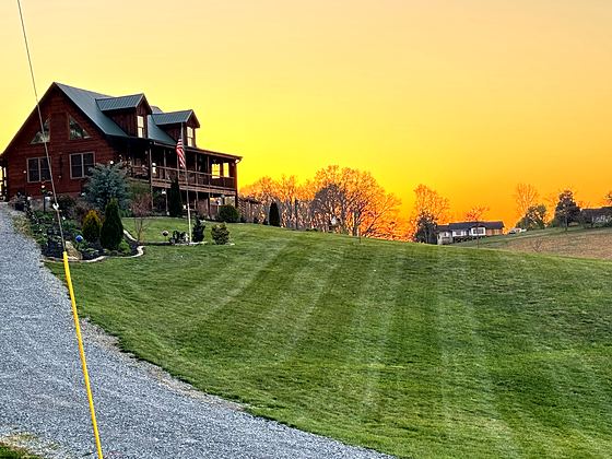 Fresh stripes rolling toward a log home at sunset